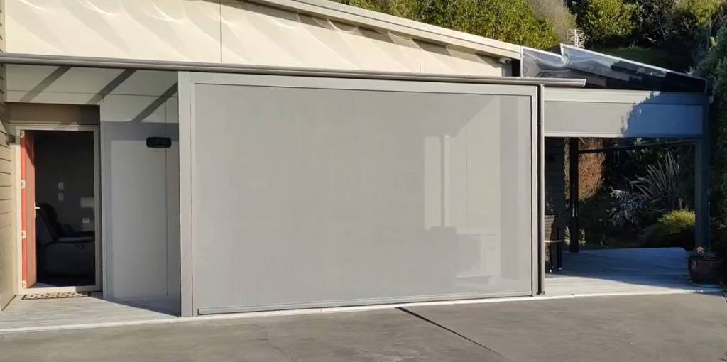 A neutral-toned outdoor blind provides privacy and shade for a modern patio area, enhancing the home's exterior.