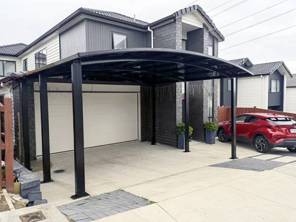 A dark double carport installed in front of a garage in Auckland, providing ample vehicle protection and enhancing curb appeal.