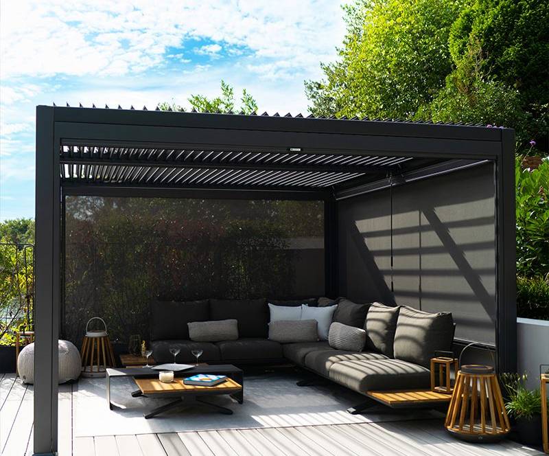Custom black aluminium louvres installed in a sunny Auckland backyard, creating a comfortable and stylish outdoor living space.