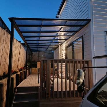 Homelovers' modern dark aluminum flat pergola, custom-built for Auckland backyards, provides stylish shade and outdoor comfort.